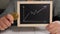 A woman is holding a gold coin bitcoin and a board with a graph of price growth.