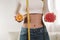 Woman holding grapefruits and orange measuring waist with tape measure