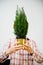 Woman holding green fir tree hiding face behind