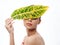 woman holding a green leaf in front of her eyes on a light background cropped view naked shoulders