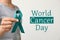 Woman holding green ribbon against background, closeup. World Cancer Day