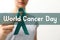 Woman holding green ribbon against background, closeup. World Cancer Day