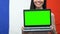 Woman holding green screen laptop against France flag, educational app traveling