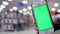 Woman holding green screen mobile phone on beautiful blurred lighting background