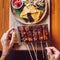 Woman is holding grilled skewers of vegan tempe