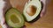 Woman holding half of fresh ripe avocado in hand, top view