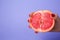 Woman holding half of juicy grapefruit on color background. Erotic concept