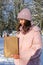 Woman holding in hand paper bag with. Postal service, delivery. Craft paper. Gift box, present. Box closeup. Blank