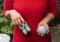 Woman holding handmade crochet baby slippers made of wool in one hand, and ball of wool with crochet needle in the other