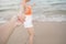 Woman holding her boyfriend hand running together on the beach