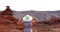 Woman holding her hat in front of the Mexican Hat landmark.
