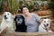 A woman holding her three Labrador dogs in a garden.