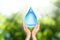 Woman holding icon of water drop on sunny background, closeup. Ecology concept