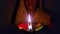 Woman holding and illuminating brightly burning clay Diya or clay oil lamp, close up Macro shot.