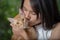 Woman holding and kissing orange short haired thai cat