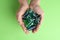 Woman holding laundry capsules on green background, top view