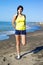 Woman holding leg stretching muscles on the beach after jogging