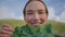 Woman holding lettuce leaf in front of face closeup. Smiling lady examining kale