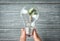 Woman holding light bulb on wooden background, closeup. Electricity saving concept