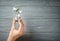 Woman holding light bulb on wooden background, closeup. Electricity saving concept