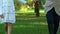 Woman holding little girl hand and walking in green park at summer, weekend