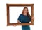 Woman holding and looking trough picture frame.