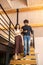 Woman holding mans arm walking down stairs indoors