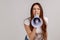 Woman holding megaphone near mouth, screaming, making announcement, paying attention.