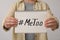 Woman holding notebook with hashtag MeToo against light background. Stop sexual assault