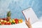 Woman holding notebook with words DIET PLAN near fruits on color background.