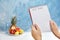 Woman holding notebook with words DIET PLAN near fruits on color background.