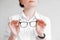 Woman holding optical glasses in a black frame on a white background. Copy, empty space