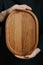 Woman holding an oval shaped wooden plate. Beautiful crockery made of real wood