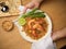 Woman holding Pad Thai dish, stir fired Thai noodles with shrimps serving with lime, beansprouts and chives