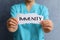 Woman holding paper piece with word Immunity on blue background, closeup