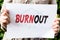 Woman is holding a paper with word burnout