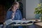 Woman holding pen and reading heap books on desk in cafe. Concept of research and searching answers in literature