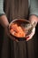 Woman holding a pet bowl with raw trout in hand. Rustic style.