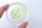 Woman holding petri dish with grape seed oil in pipette and slice of green grape. Pure essential skin care oil. Spa treatment