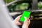 A woman is holding a phone with a green screen on the background of the car. a business woman stands with a phone by the car