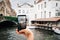 Woman holding a phone taking a photo to Bruges cityscape