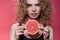 Woman holding piece of grapefruit isolated on pink