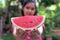 Woman is holding a piece of watermelon. Each pieces are red, sweeten, hydra, and nice. It is popular fruits in Summer because wate
