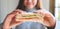 A woman holding a piece of whole wheat sandwich to eat