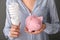 Woman holding piggy bank with light bulb, closeup. Electricity saving concept