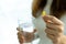 Woman holding pills or drug capsules and a glass of water in hand. Young woman take medication, feeling sick and stomach pain or t