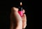 Woman holding pink lighter on black background, closeup