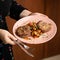 Woman holding plate of food and cutlery. Fried minced meat cutlet with vegetables on platter in female hands. Close up