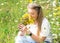 Woman holding a posy and sniffing flowers on a meadow in the afternoon