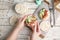 Woman holding puffed rice cake with prosciutto and cucumber at white wooden table